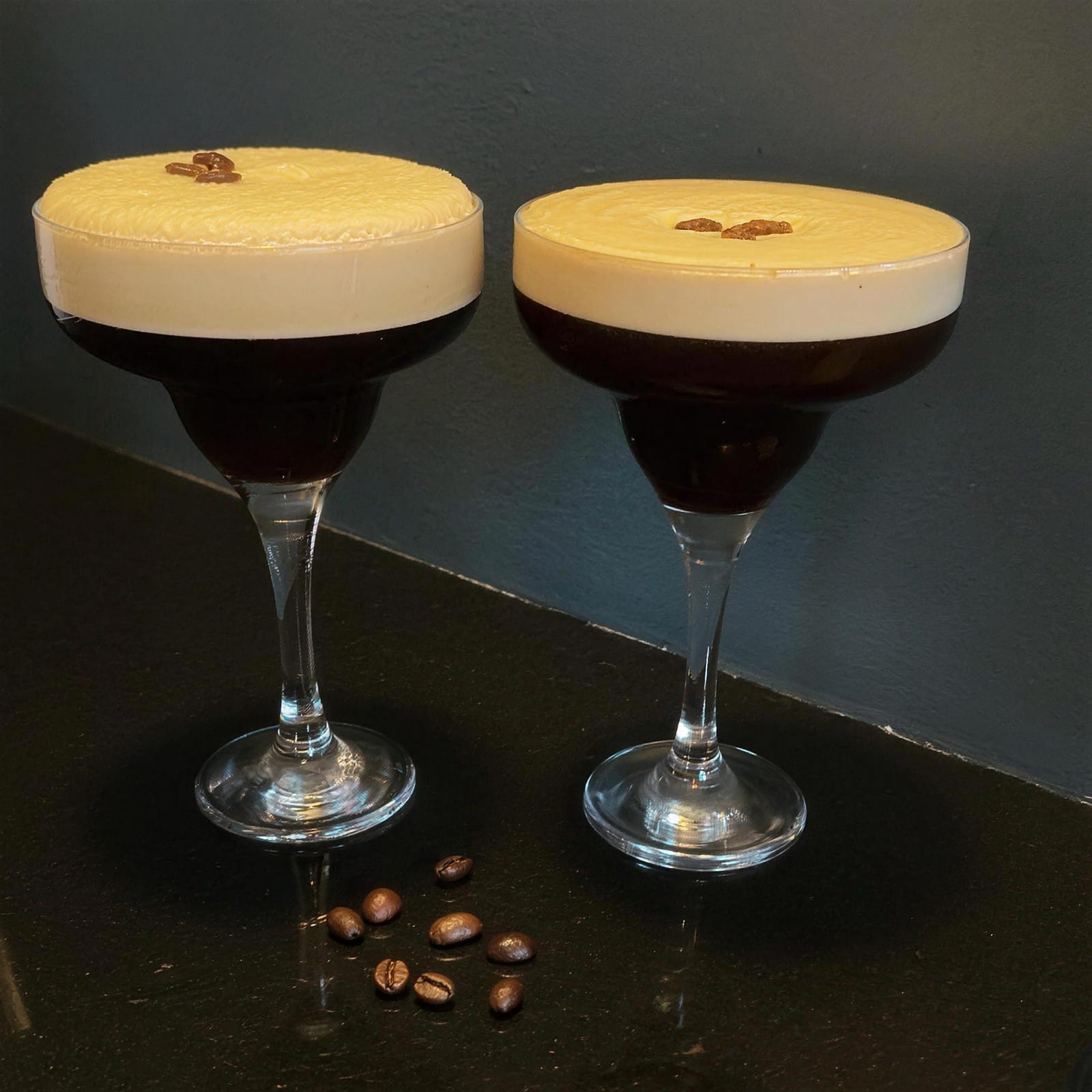 Two espresso martinis topped with coffee beans on the bar